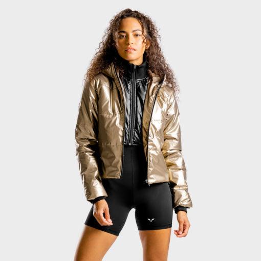 Woman wearing a shiny gold jacket and black cycling shorts against a white background.