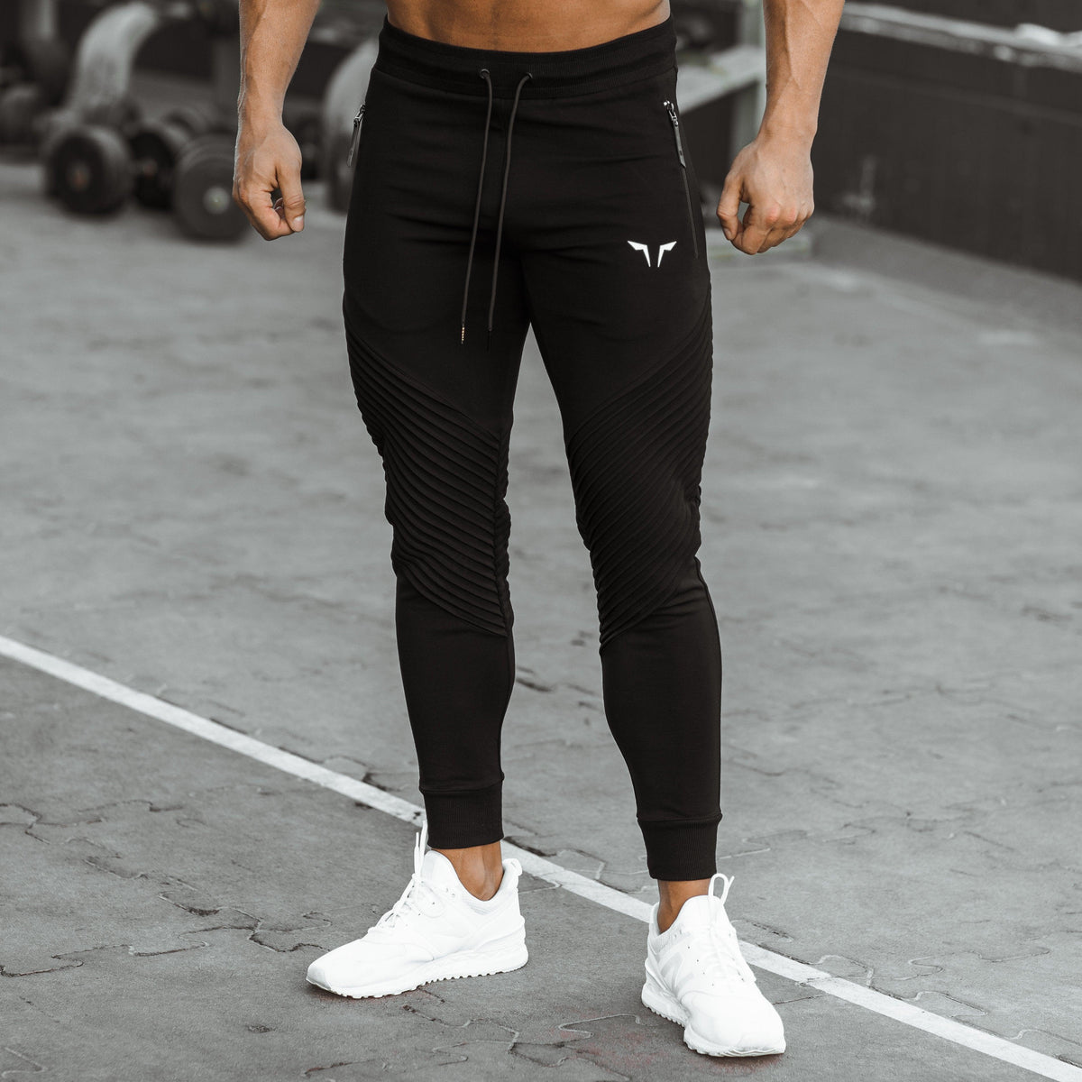 Close-up of black Squat Wolf joggers with ribbed knee panels and zippered pockets.