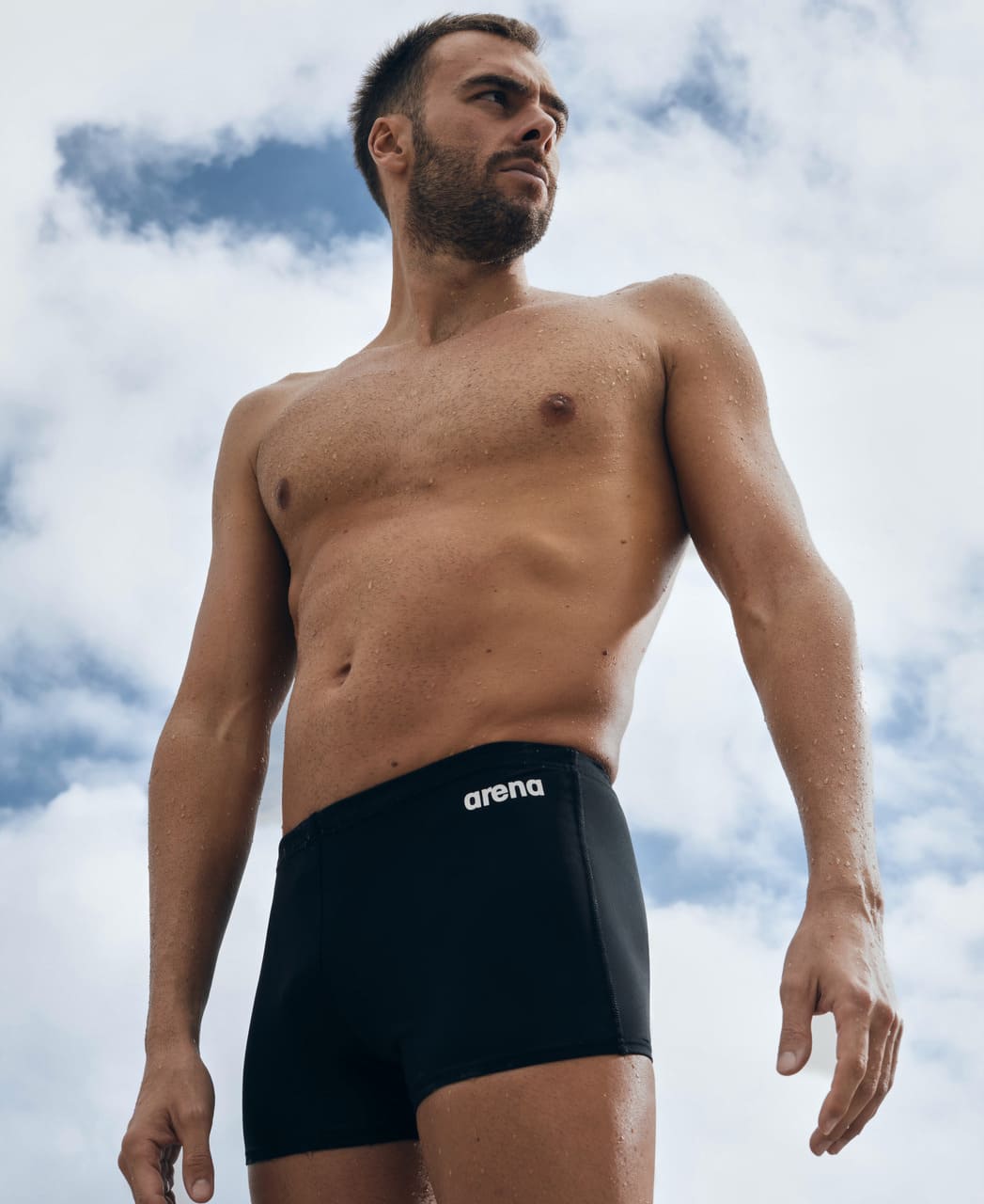 Team klórþolin sundskýla fyrir herra í svört frá Arena. Sundskýlan er framleidd úr MaxLife Eco sundfataefni Arena úr 100% pólýester (að hluta endurunnu pólýester) sem gerir þær að góðum kosti fyrir íslenskar sundlaugar með klór. Lífstílsmyndin sýnir karlmann standa í Team sundskýlunni